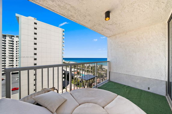 View from a balcony overlooking nearby buildings and the ocean in the background.