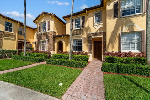 Front view of a two-story house with stone accents and brown shutters.
