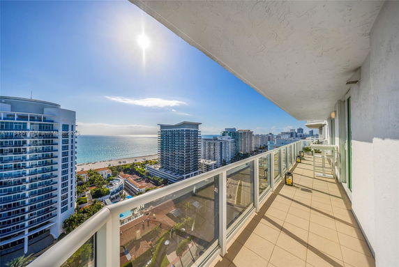 High-rise balcony view overlooking the ocean and surrounding buildings.