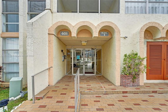 Front view of a building entrance with arched design and tiled walkway.