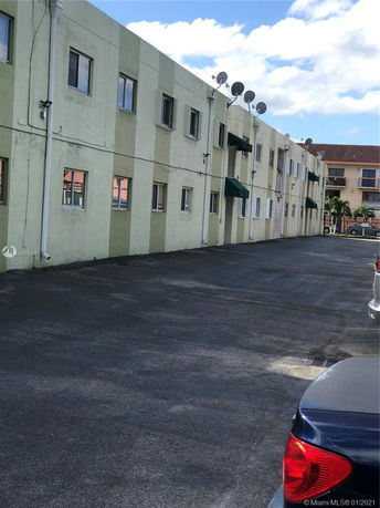 Side view of a two-story apartment building with satellite dishes.