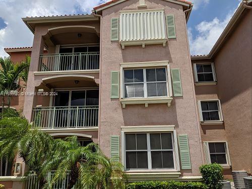 Front view of a multi-story apartment building with balconies and green shutters.