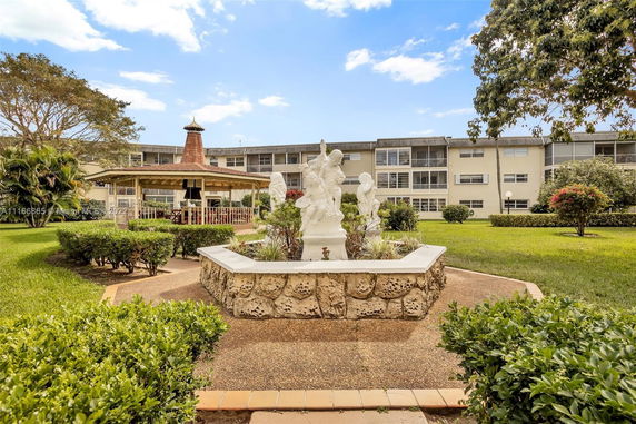 View of an apartment complex with a central garden featuring a statue and a gazebo.
