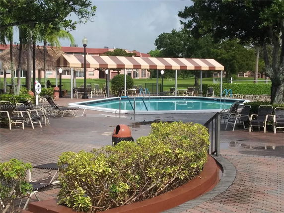 Outdoor swimming pool area with chairs and a canopy.