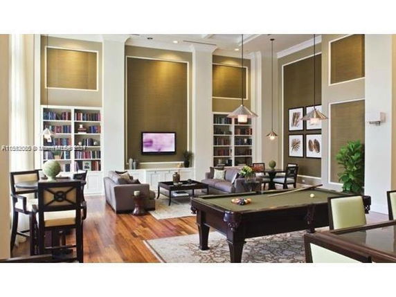 Interior of a recreational room with seating, a pool table, and bookshelves.