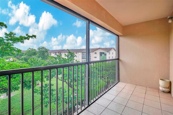 Balcony view overlooking a green landscape with nearby buildings.