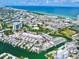 Panoramic view of a coastal city with buildings, waterways, and the ocean in the distance.