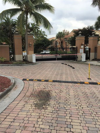 Front view of a gated residential area with palm trees.
