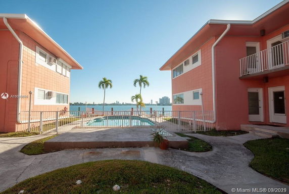 Outdoor area between two buildings with a swimming pool and a view of the water.
