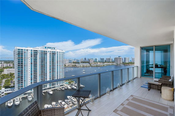 Panoramic view from a balcony overlooking a cityscape and water with boats.