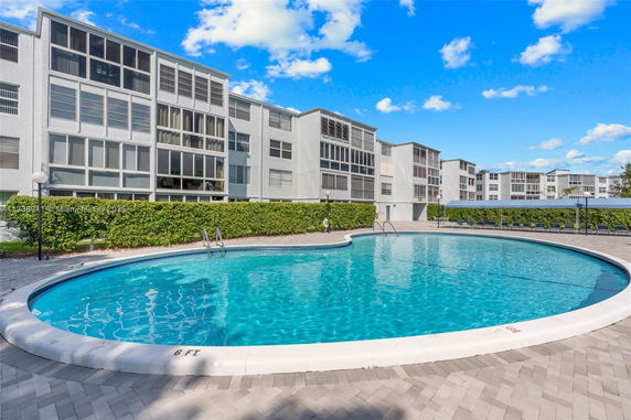 Outdoor swimming pool in front of a multi-story residential building.