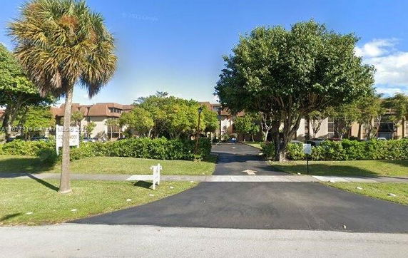 Front view of a residential building with multiple units and surrounding greenery.