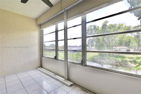 Panoramic view from a balcony with windows overlooking trees and a residential area.