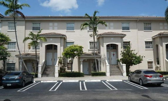 Front view of a multi-story residential building with a tiled roof and multiple entrances.