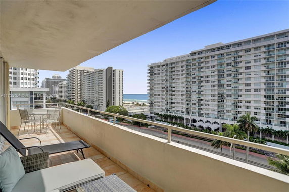 Panoramic view from a balcony overlooking high-rise buildings and the ocean in the distance.