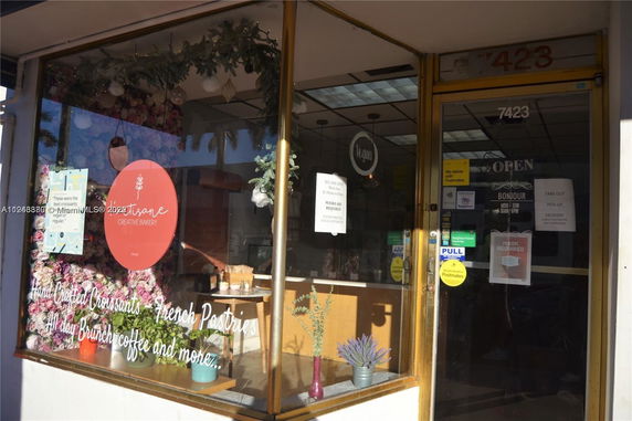 Front view of a bakery with large windows and door displays logos and signs.