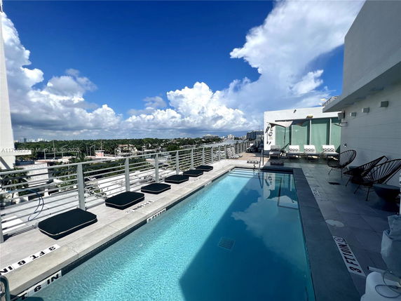 Rooftop swimming pool with lounge chairs and a view of the city.