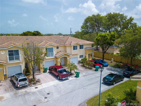 Front view of a two-story townhouse with attached garages and parked cars.