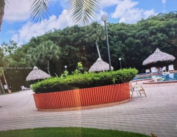 Outdoor area with a swimming pool and thatched-roof structures.