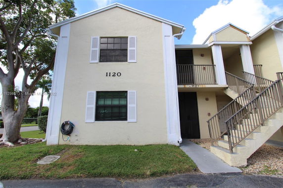 Front view of a two-story townhouse with external stairs and a numbered facade.