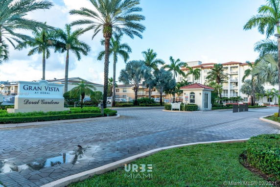 Front view of a multi-story residential building with a gated entrance and palm trees.
