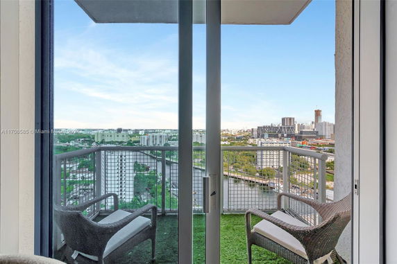Panoramic view from a high-rise balcony overlooking a cityscape with buildings and a river.