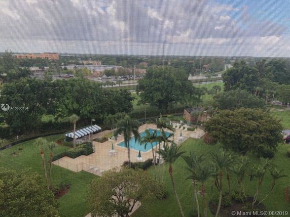 View of a pool area with surrounding trees and distant buildings.