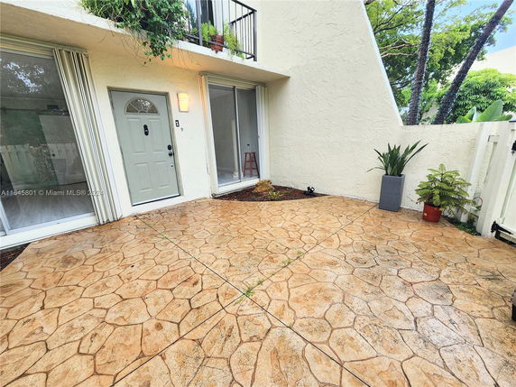 Front view of a building with a textured patio and large sliding doors.