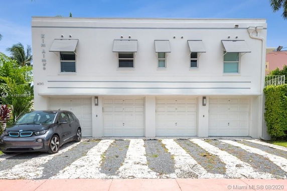 Front view of a two-story building with garage doors and a car parked in front.