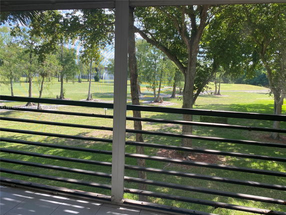 View from a balcony showing a grassy area with trees in the background.