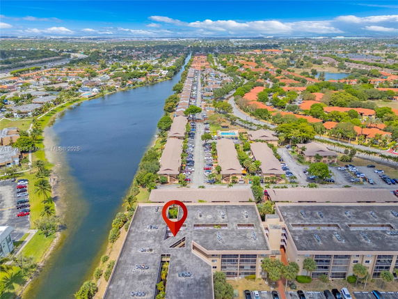 Panoramic view of residential area with large buildings, parking areas, and a nearby waterway.