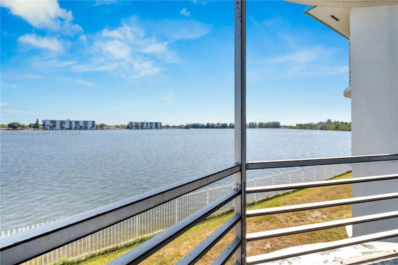 View from a balcony overlooking a body of water with distant buildings.