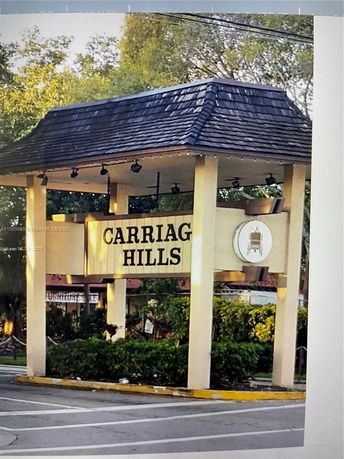 Sign reading Carriag Hills with a decorative roof, positioned by a roadside.