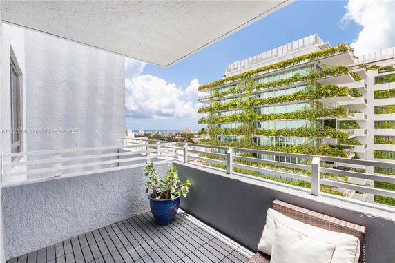View from a balcony showing a modern building with plants on its facade.