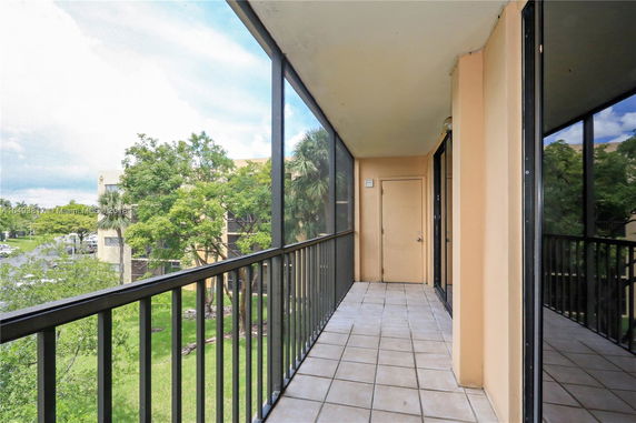 View from a screened balcony overlooking trees and neighboring buildings.
