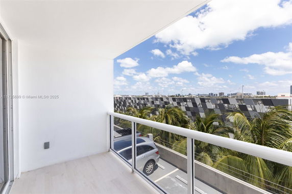 Balcony view overlooking a parking area and adjacent buildings.
