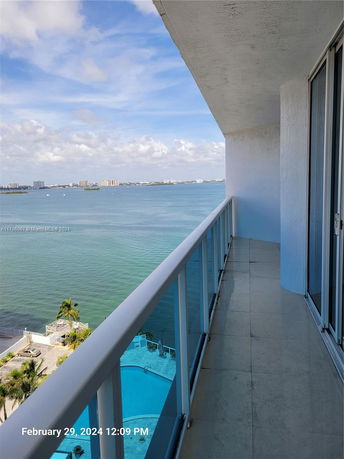 Balcony view overlooking a large body of water with distant buildings.