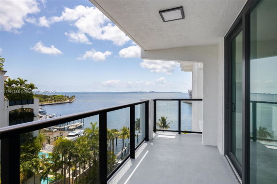 Balcony with a view of the ocean and nearby buildings.