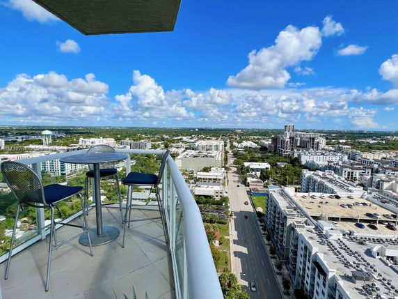 Panoramic view from a high-rise balcony overlooking city buildings and roads below.
