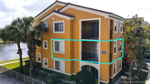 Front view of a multi-story apartment building with a yellow facade and balconies.