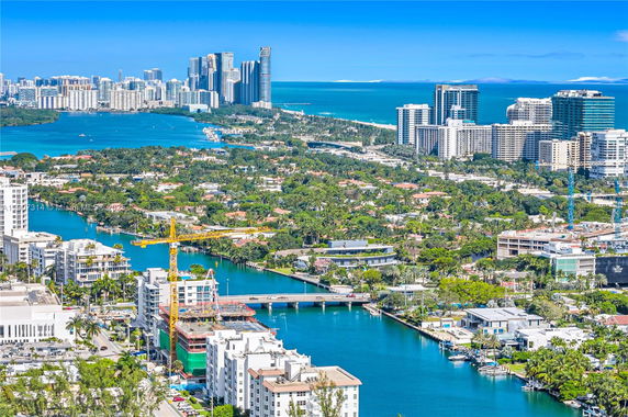 Panoramic view of a coastal cityscape with buildings, waterways, and greenery.
