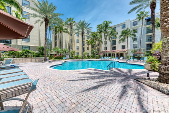 View of a multi-story residential building with a swimming pool in the courtyard.