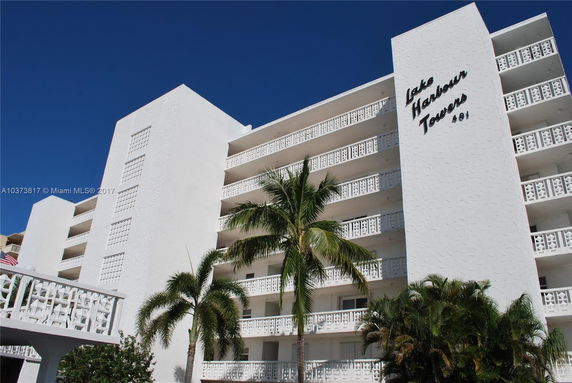 Front view of a multi-story white building with balconies and decorative latticework.