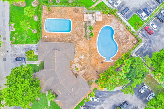 Aerial view of a property with two swimming pools and a surrounding parking area.