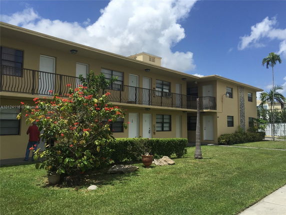 Front view of a two-story beige apartment building with balconies.