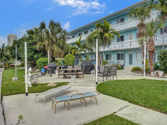 View of a multi-story building with outdoor seating and palm trees.