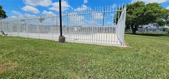 Fenced area with an empty swimming pool and nearby buildings.