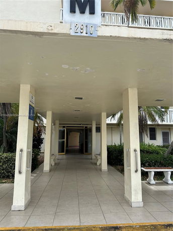 Entrance view of a building with a covered walkway and signage 'M 2910'.