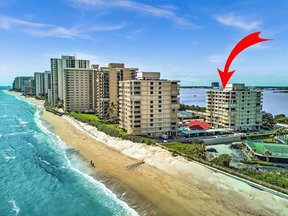 Aerial view of beachfront condominium buildings with a water body on the other side.
