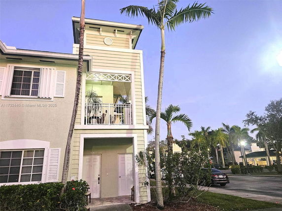 Front view of a two-story house with a balcony and decorative shutters.
